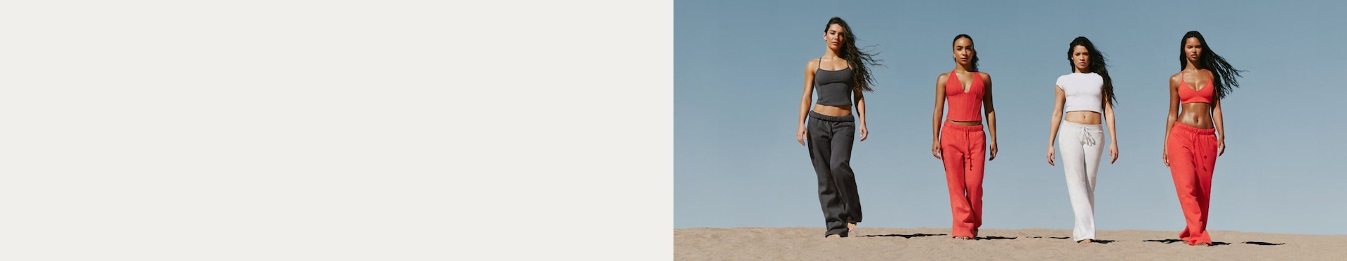 Group of models in the desert in a mix of dark grey, white, and orange outfits.