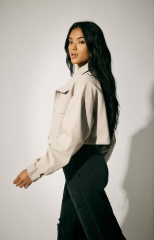 Model is wearing a cropped jacket, black crop top and bottoms.
