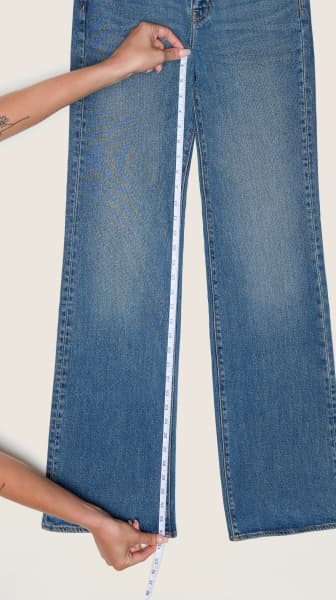 Place the measuring tape from the crotch seam to the hem on a pair of jeans.
