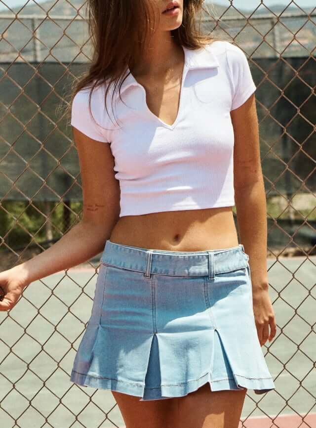 Model wearing a white top and a jean mini skirt.