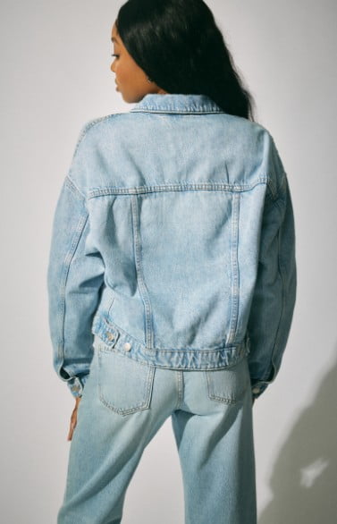 Model wears a denim jacket with a denim top and jeans.