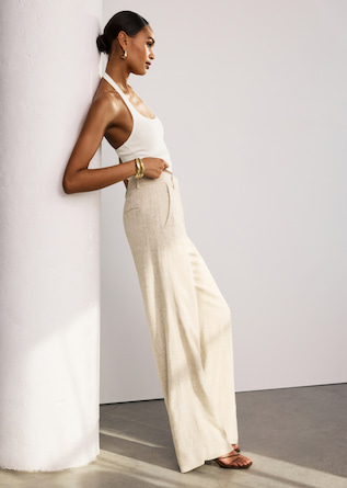Model is wearing a white halter top with off white pants.