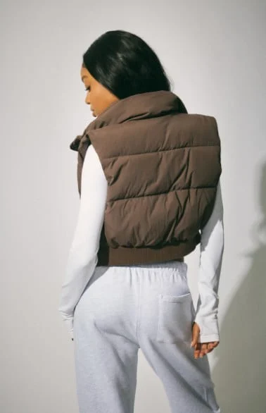 Model wears a vest over a white sweater with sweatpants.